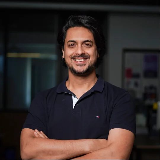 Ameet Palkar smiling, arms crossed, in a studio