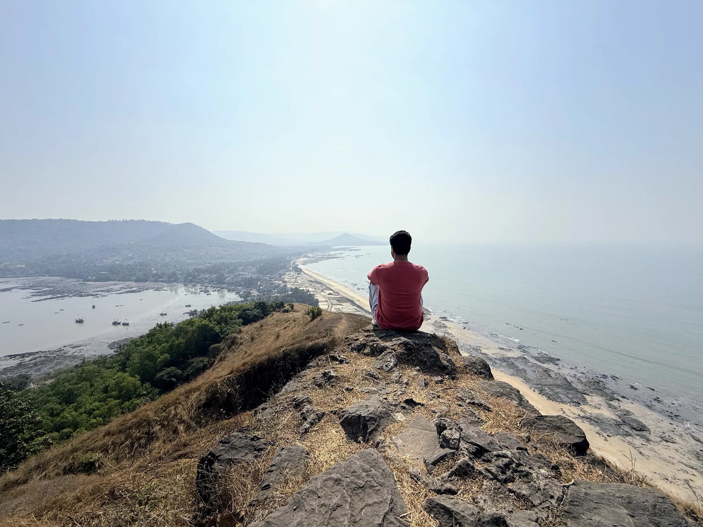 Sitting on a rocky hilltop, looking out over a long coastline and the sea