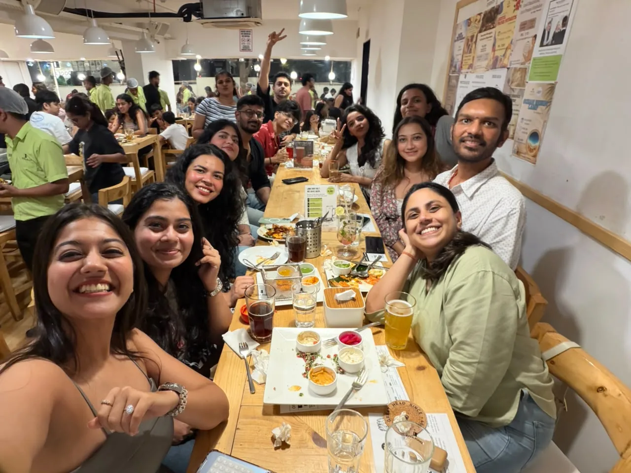 A big group of colleagues laughing around a long restaurant table at a team dinner