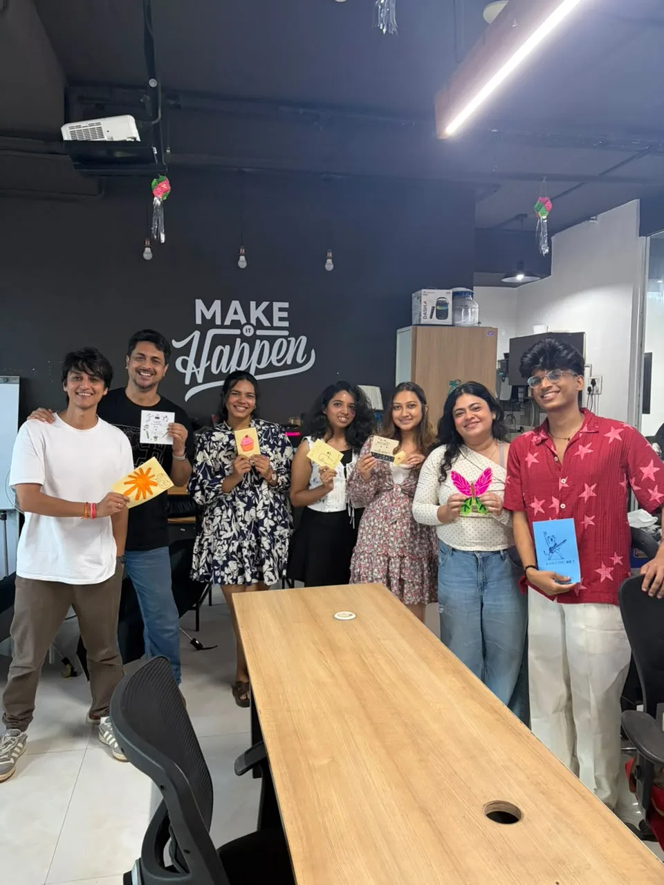Seven colleagues smiling in the studio, each holding up a handmade card