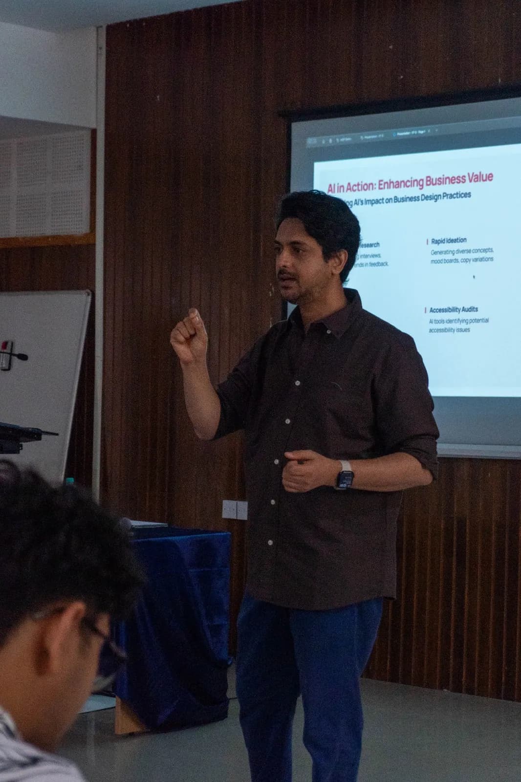 Ameet making a point beside a slide about AI enhancing business value